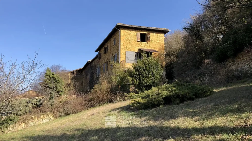 Vue extérieure d'une maison ancienne en pierre dorée avant achat immobilier