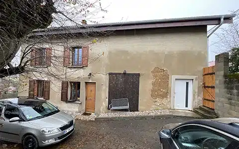 Vue extérieure d'un bâtiment en pisé présentant des signes d'humidité